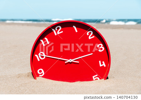 a close-up of a red clock half buried in the sand a close-up of a red clock half buried in the sand 140704130