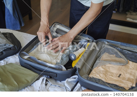 a man seals a vacuum storage bag with clothes a man seals a vacuum storage bag with clothes 140704138