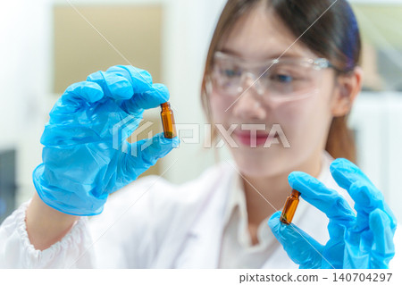 Scientist in lab holding vials of liquid showcasing modern research techniques and technology in a professional environment Scientist in lab holding vials of liquid showcasing modern research techniques and technology in a professional environment 140704297