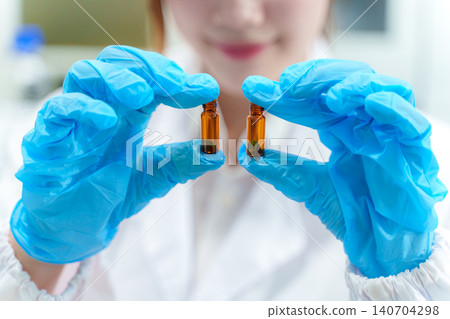 Scientist in lab holding vials of liquid showcasing modern research techniques and technology in a professional environment Scientist in lab holding vials of liquid showcasing modern research techniques and technology in a professional environment 140704298