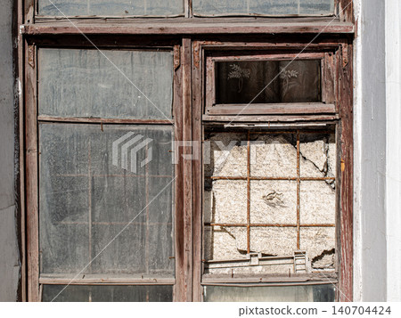 Fragment of an ancient wooden frame with a small vent on a dusty ruined window Fragment of an ancient wooden frame with a small vent on a dusty ruined window 140704424