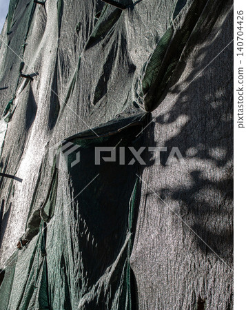 Green safety construction netting covering a building facade architecture backdrop Green safety construction netting covering a building facade architecture backdrop 140704426