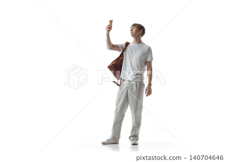 Teen boy taking selfie with smartphone and shoulder bag. 140704646