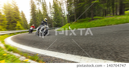 Sport motorcycle rider cornering on a winding mountain pass. Motion blur and dynamic perspective emphasize speed, control, performance riding and scenic road adventure. Sport motorcycle rider cornering on a winding mountain pass. Motion blur and dynamic perspective emphasize speed, control, performance riding and scenic road adventure. 140704747