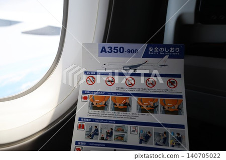 A person sitting in an airplane seat reading the safety information card. 140705022