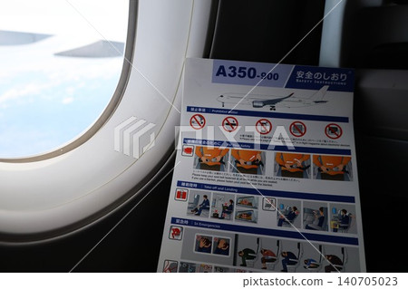 一名乘客坐在飛機座位上閱讀安全須知卡。 一名乘客坐在飛機座位上閱讀安全須知卡。 140705023