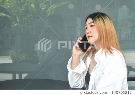 business woman sitting on chair and using mobile phone in community mall garden business woman sitting on chair and using mobile phone in community mall garden 140705212