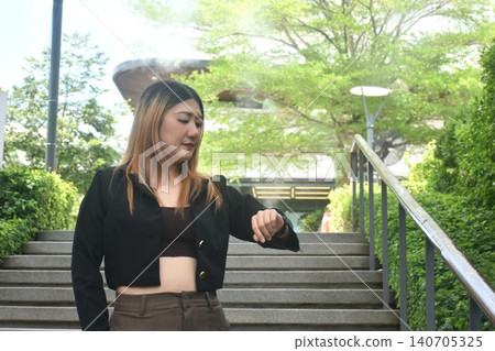 business woman looking ang checking time on smart watch in community mall garden 140705325