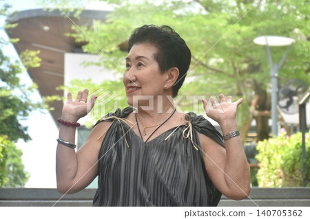 elder woman strong and healthy posing and smiling in community mall garden 140705362