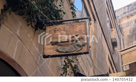 A quaint sign board with a picture of vegetable on a plate engraved on it in the old town A quaint sign board with a picture of vegetable on a plate engraved on it in the old town 140705432