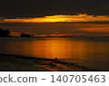 Calm ocean waters reflecting soft golden light beneath a dramatic sky creating a peaceful seascape horizon view 140705463