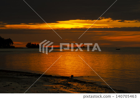 Calm ocean waters reflecting soft golden light beneath a dramatic sky creating a peaceful seascape horizon view 140705463