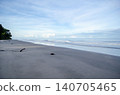 Tropical beach sunset scene with silhouetted palm trees framing a colorful evening sky over the ocean horizo 140705465