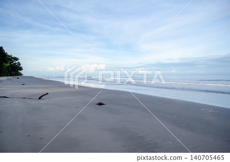 Tropical beach sunset scene with silhouetted palm trees framing a colorful evening sky over the ocean horizo 140705465