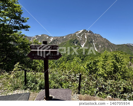 The summit marker of Mt. Tanigawa and the fresh greenery with lingering snow on a perfectly clear, cloudless day at Mt. Tanigawa (Minakami Town, Gunma Prefecture) 140705934