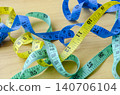 Multiple measuring tapes scattered across a wooden surface representing fitness planning and lifestyle improvement efforts 140706104