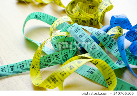 Colorful measuring tapes intertwined on a light background illustrating weight loss planning 140706106