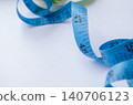 Curved blue measuring tape on a clean background emphasizing healthy living objectives. 140706123