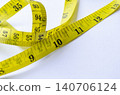 Yellow measuring tape stretched diagonally across a white surface symbolizing weight loss journeys and nutritional awareness. 140706124