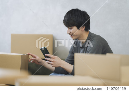 一名年輕男子手持智慧型手機,周圍堆滿了紙箱——動態影像 一名年輕男子手持智慧型手機,周圍堆滿了紙箱——動態影像 140706439