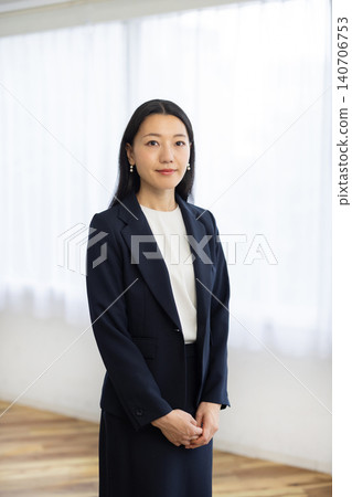 A young Japanese businesswoman smiles at the camera from a window. A young Japanese businesswoman smiles at the camera from a window. 140706753