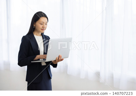 一位年輕的日本女商人正在窗邊使用筆記型電腦。 140707223
