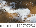The foam of ocean waves on wet sand creates an abstract texture. 140707238