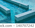 A modern pool with blue water and geometric concrete platforms. 140707242