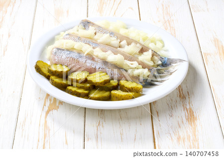 Dutch herring and onions and pickles on plate. traditional Dutch delicacy on kitchen table, selective focus. Dutch herring and onions and pickles on plate. traditional Dutch delicacy on kitchen table, selective focus. 140707458