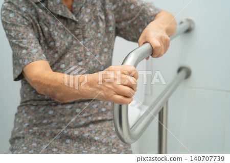 Asian elderly woman use toilet security support rail in bathroom. 140707739