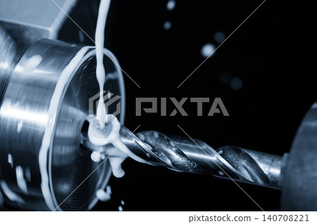 Close-up of a lathe machine drill tool making a hole in a metal part with liquid coolant. 140708221