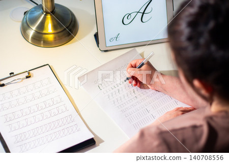 Quiet scene of woman writing with pen. Training accurate handwriting. Therapeutic habit to reduce anxiety and increase clarity. Calmness and digital detox Quiet scene of woman writing with pen. Training accurate handwriting. Therapeutic habit to reduce anxiety and increase clarity. Calmness and digital detox 140708556