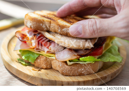 Hand Holding Fresh Club Sandwich with Bacon, Ham, Cheese and Grilled Chicken Hand Holding Fresh Club Sandwich with Bacon, Ham, Cheese and Grilled Chicken 140708569