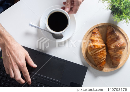 Remote Work Breakfast with Coffee and Croissants on Home Office Desk 140708576