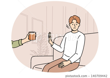 Determined man refuses alcohol, demonstrates stop gesture, sitting on sofa near hand with whiskey 140709442