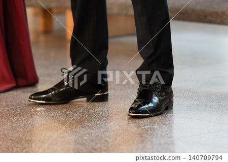 Shiny black dress shoes paired with dark suit trousers Shiny black dress shoes paired with dark suit trousers 140709794