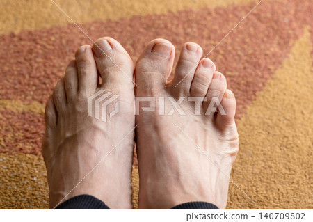Bare adult feet and toes rest close-up on a warm carpet Bare adult feet and toes rest close-up on a warm carpet 140709802