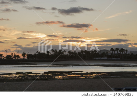Tropical beach sunset reflecting in calm ocean water 140709823