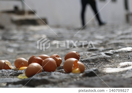 Broken eggs lying on a rough cobblestone pavement 140709827
