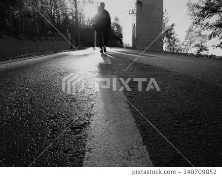 Person walking on empty road towards bright sunlight Person walking on empty road towards bright sunlight 140709852