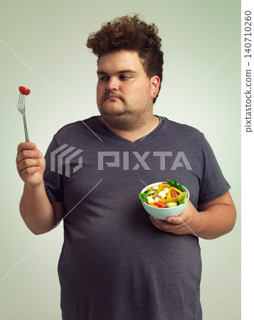 Unhappy, man and salad in studio for weight loss, healthy food and organic nutrition for wellness. Male person, plus size and disgust with meal for vitamin c, detox or lifestyle change for diet Unhappy, man and salad in studio for weight loss, healthy food and organic nutrition for wellness. Male person, plus size and disgust with meal for vitamin c, detox or lifestyle change for diet 140710260