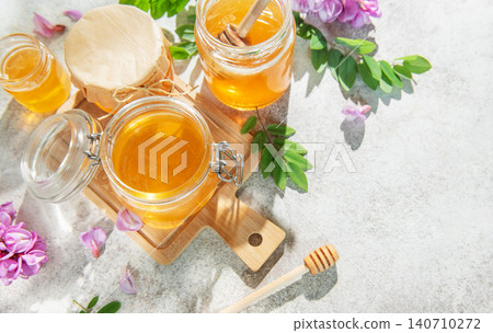 Golden acacia honey in jars with dipper, flowers Golden acacia honey in jars with dipper, flowers 140710272