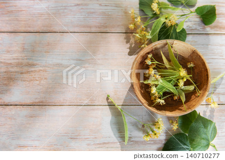 Linden flowers in wooden bowl on light wood Linden flowers in wooden bowl on light wood 140710277