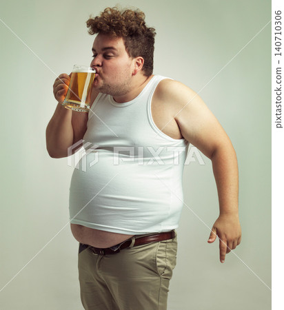 Chubby, weight gain and beer for man in studio with alcohol for unhealthy habit, plus size and humor. Overweight person with glass in hand and drinking with fat stomach for comedy, joke and funny 140710306