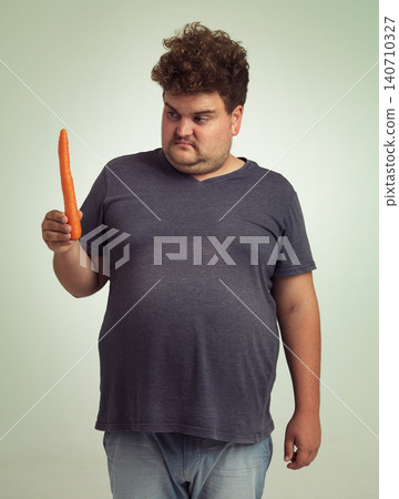 Man, vegetables and carrot in studio with thinking for healthy snack, detox and vitamin c for wellness. Plus size, male person and unhappy with organic food for nutrition, lifestyle and diet Man, vegetables and carrot in studio with thinking for healthy snack, detox and vitamin c for wellness. Plus size, male person and unhappy with organic food for nutrition, lifestyle and diet 140710327