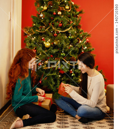 Christmas, happy and women with presents, tree with decor in living room for holiday. Gift giving, smile and family sitting on floor together, Christian celebration on Xmas eve with mother and child Christmas, happy and women with presents, tree with decor in living room for holiday. Gift giving, smile and family sitting on floor together, Christian celebration on Xmas eve with mother and child 140710360