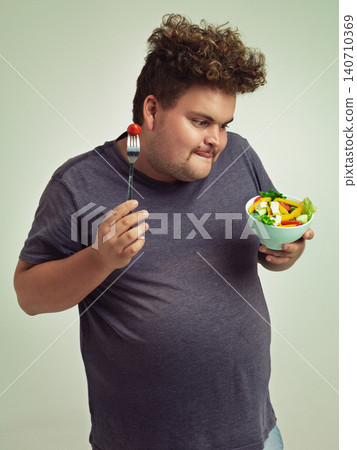 Happy, plus size and man with salad in studio for healthy diet, natural nutrition and weight loss. Male person, organic food and tomato on fork with thinking for vitamin c, detox or vegan change Happy, plus size and man with salad in studio for healthy diet, natural nutrition and weight loss. Male person, organic food and tomato on fork with thinking for vitamin c, detox or vegan change 140710369