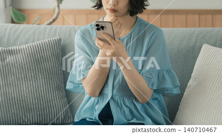 A woman thinking while using her smartphone A woman thinking while using her smartphone 140710467