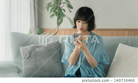 A woman thinking while using her smartphone 140710468