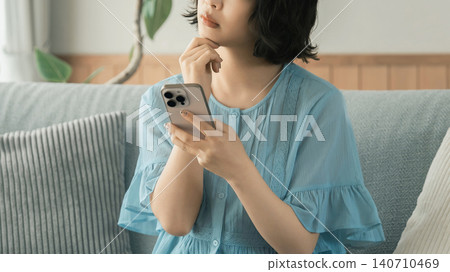 A woman thinking while using her smartphone A woman thinking while using her smartphone 140710469